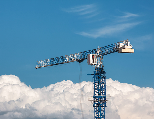 Construction crane blue and white above the clouds on the blue sky background
